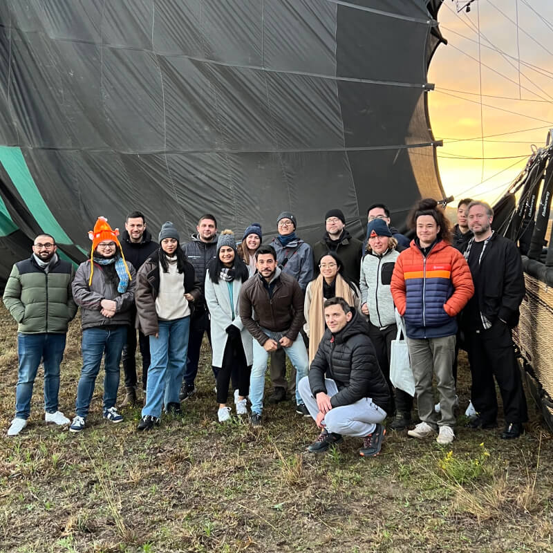 NurtureCloud team group photo in front of a hot air balloon during an off-site event